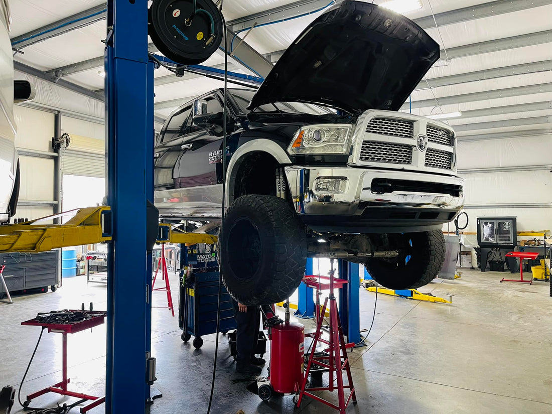 black pickup truck on shop lift with hood open inside automotive shop