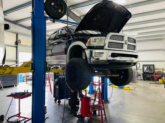 black pickup truck on shop lift with hood open inside automotive shop