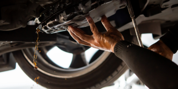 close up of mechanic changing transmission fluid under a vehicle